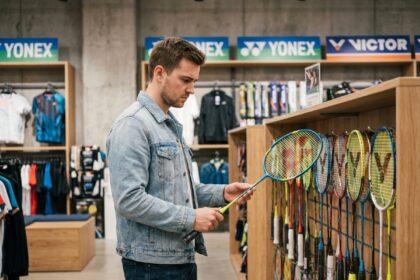 Jeune homme examine un raquette de badminton dans un magasin moderne